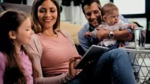 clm feliz mae e filha usando tablet digital enquanto o pai esta segurando um menino em casa