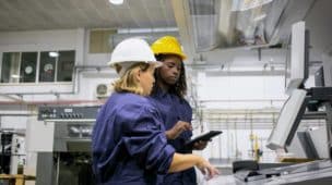 clm_feminino-funcionário-industrial-ensinando-colega-operar-máquina-apontando-placa-de-controle-usando-tablet